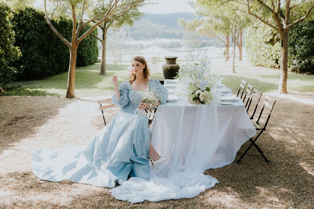 Ethereal Fashion Editorial Wedding Image of a Bride in a Blue Dress at a courtyard table. Expensive, classy, elegant. Hunter Valley, Sydney, Southern highlands, Nsw Australia. How to find your dream wedding photographer.
